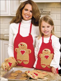 a woman and girl in red aprons with gingerbread cookies