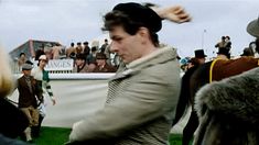 a man is standing in front of an audience at a horse show with other people