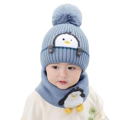 a small child wearing a blue hat and scarf with a penguin on it's head