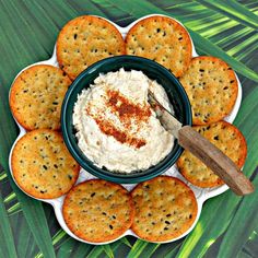 crackers and dip in a bowl on a platter with palm leaves around it