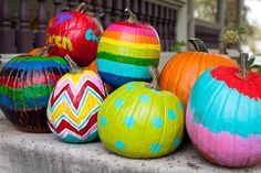 colorful painted pumpkins sitting on top of a cement slab