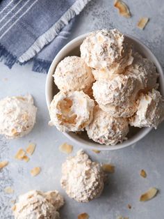 a white bowl filled with cookies on top of a gray counter next to a blue towel