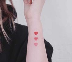 a woman with a small red heart tattoo on her arm