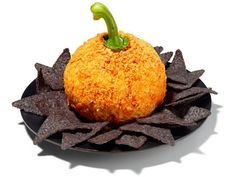 a black plate topped with an orange ball covered in cheese and tortilla chips