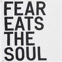 a sign that says fear eats the soul with black letters on white paper behind it