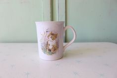 a coffee cup with a cat on it sitting on a table