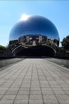 a large shiny ball sitting on top of a sidewalk