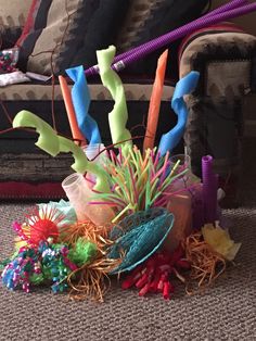 a bunch of colorful objects sitting on the ground in front of a couch and chair