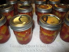 jars filled with pickles sitting on top of a white tablecloth covered countertop