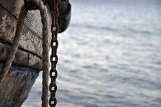 an old wooden boat with chains hanging from it's side