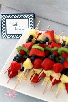 fruit kabobs are arranged on a white plate