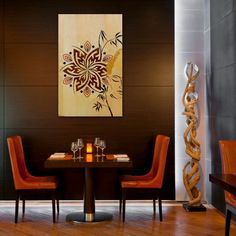 a dining room table with two chairs and a painting on the wall