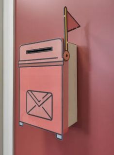 a mailbox mounted to the side of a pink wall with an envelope sticking out of it