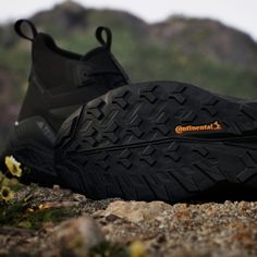 a pair of black shoes sitting on top of a rocky ground