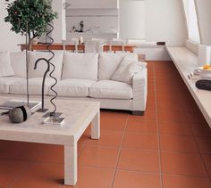 a white couch sitting next to a coffee table on top of a tiled living room floor