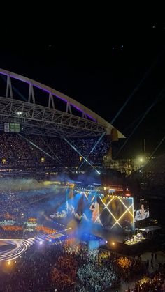 an aerial view of a stadium at night with lights on the stage and people in the stands