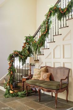 the stairs are decorated with garlands and pine cones for an elegant christmas display in this entryway