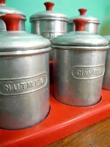 four metal canisters sitting on top of a red shelf