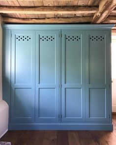 an empty room with blue cupboards and wood flooring on the walls, in front of a wooden ceiling