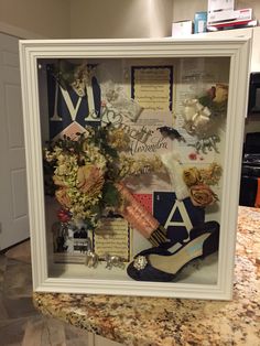 a display case filled with shoes and flowers on top of a granite countertop in a kitchen