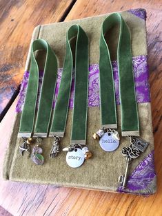 six pairs of green velvet ties with charms on them sitting on top of a wooden table