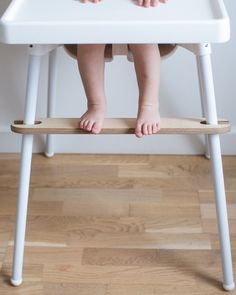 a toddler sitting in a high chair with his feet on the edge of it