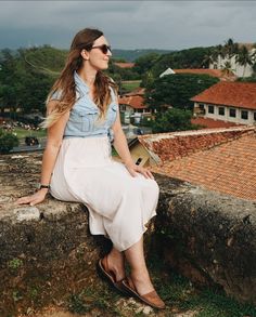 a woman sitting on top of a stone wall