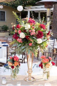 two vases filled with flowers sitting on top of a white tablecloth covered table