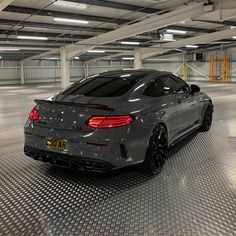 a grey sports car parked in a parking garage with no one on the ground around it