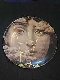 a plate with a woman's face painted on the front and side, sitting on a black surface