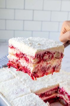 someone is holding up a piece of cake with white frosting and raspberry filling