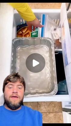 a man standing in front of an open refrigerator holding a tray with food on it