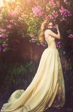 a woman in a long dress standing next to flowers