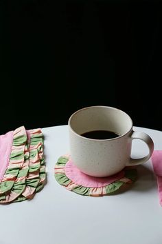 a cup of coffee sitting on top of a white table next to pink napkins