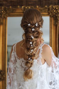 a woman with long hair and flowers in her hair is looking at herself in the mirror