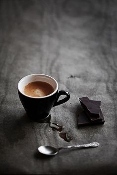 a cup of coffee sitting on top of a table next to spoons and napkins