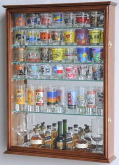 a wall mounted display case filled with lots of bottles and glasses on top of shelves