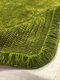 a close up of a green rug on a bed