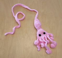 a pink crocheted octopus with black eyes on it's head and tail