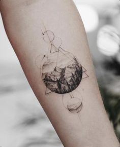 a tattoo on the arm of a person with mountains in the background and stars above it