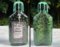 two glass bottles with green and black designs on them, one has a key in it