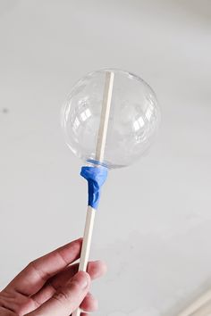 a hand holding a lollipop with a blue stick sticking out of the top