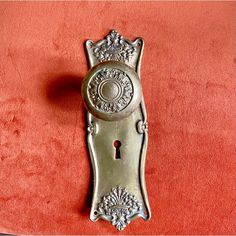 an ornate metal door handle on a red velvet surface with a keyhole in the middle