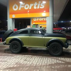 a green and black car parked in front of a torrits store at night