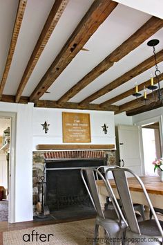 a living room with a fire place and wooden beams on the ceiling, along with two chairs