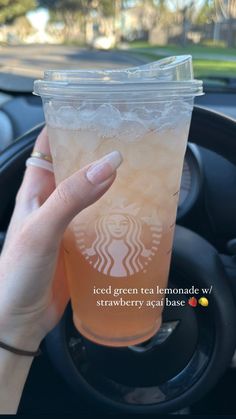 a woman holding up a cup of iced tea