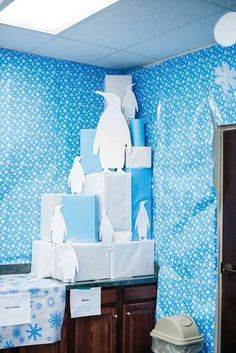 the room is decorated in blue and white with penguin paper cutouts on the wall