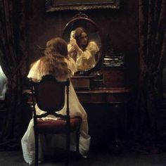 a woman sitting at a desk in front of a mirror