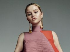 a woman in a pink and orange dress with gold hoop earrings on her left ear