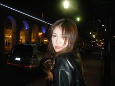 a woman standing in front of a car at night